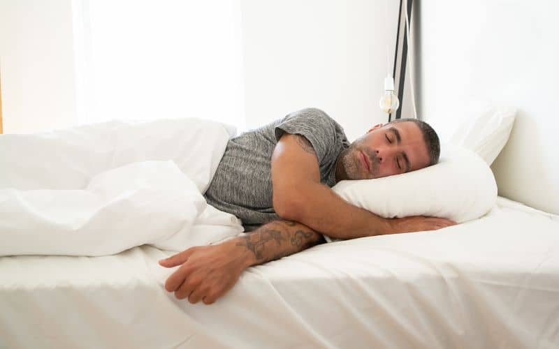 Les coussins chauffants : Adopter l'alternative chauffante pour une vie sans douleur Homme allongé dans son lit, la tête sur un coussin chauffant.