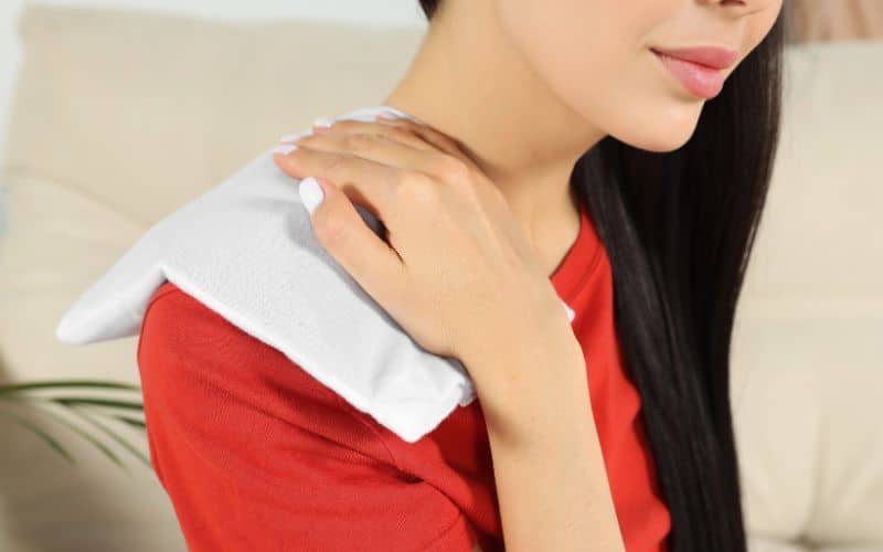 Les coussins chauffants : Adopter l'alternative chauffante pour une vie sans douleur Femme, avec un coussin chauffant sur l'épaule pour soulager sa douleur.