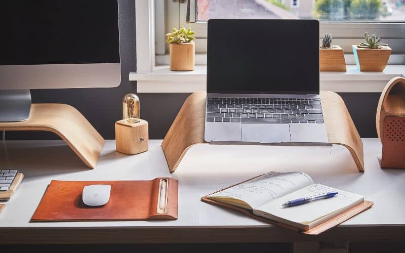 Bureau de télétravail avec des accessoires ergonomique tel qu'un tapis de souris, un rehausseur pour ordinateur portable, pareil pour un ordinateur fixe.