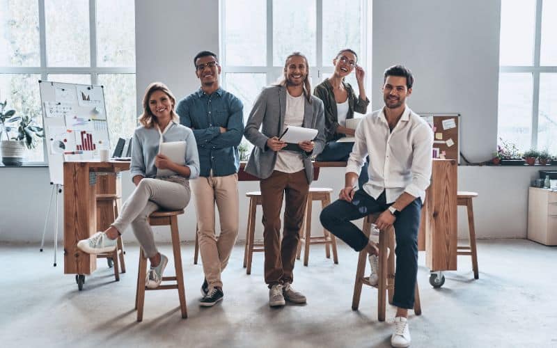 Groupe de personne qui travaillentensembles,à côté d'une table et de tabourets hauts.